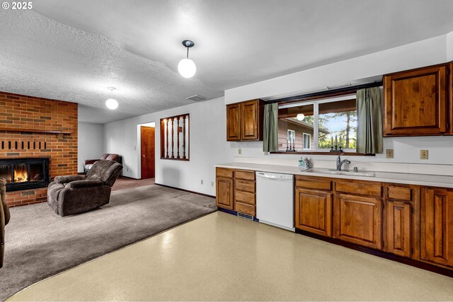 kitchen featuring dishwasher, a sink, light countertops, brown cabinetry, and a fireplace