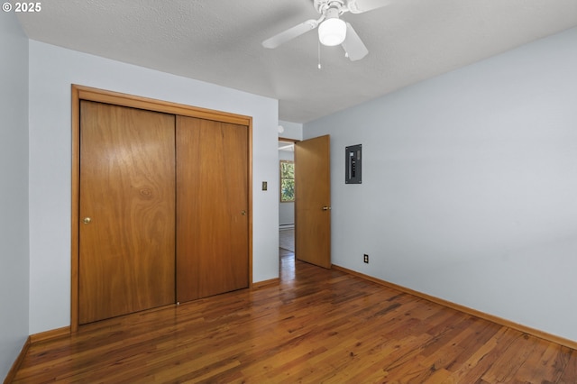 unfurnished bedroom featuring wood finished floors, electric panel, a closet, and baseboards