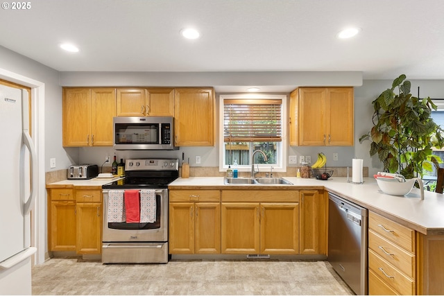 kitchen with a sink, appliances with stainless steel finishes, a peninsula, and light countertops