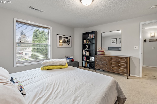 carpeted bedroom featuring baseboards, a textured ceiling, and visible vents