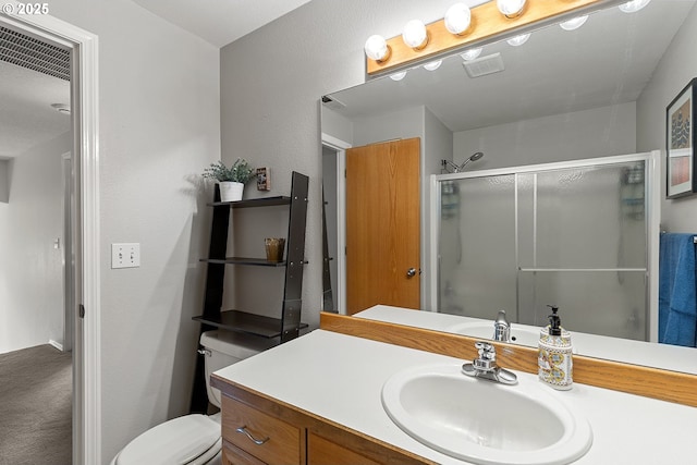 bathroom featuring a textured wall, vanity, toilet, a shower stall, and visible vents