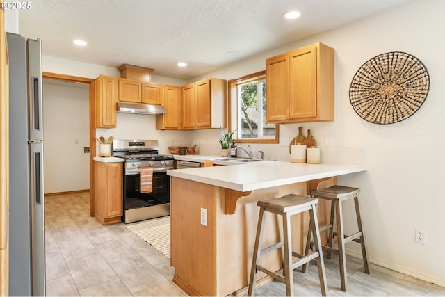 6837 SE 84th Ave, Portland, OR 97266 - kitchen featuring stainless steel appliances, under cabinet range hood, a peninsula, a breakfast bar, and light countertops
