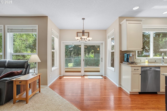 4710 SW Joshua St, Tualatin, OR 97062 - kitchen with dishwasher, a chandelier, light wood-style floors, white cabinetry, and backsplash