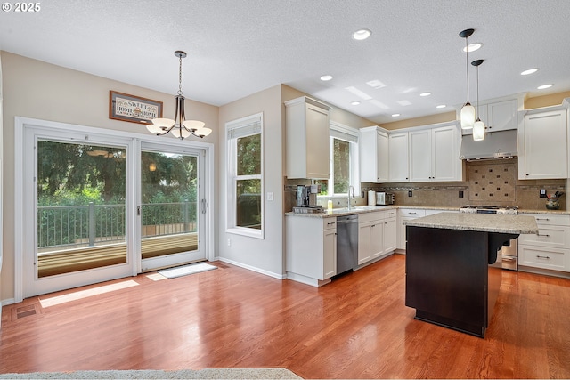 4710 SW Joshua St, Tualatin, OR 97062 - kitchen with appliances with stainless steel finishes, under cabinet range hood, a chandelier, decorative backsplash, and light wood-type flooring