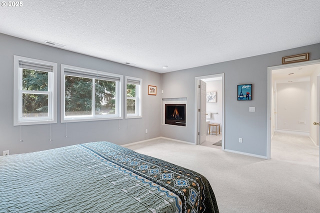 4710 SW Joshua St, Tualatin, OR 97062 - carpeted bedroom featuring a textured ceiling, ensuite bathroom, and a lit fireplace