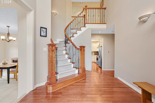 4710 SW Joshua St, Tualatin, OR 97062 - stairway featuring wood finished floors, a chandelier, and a towering ceiling