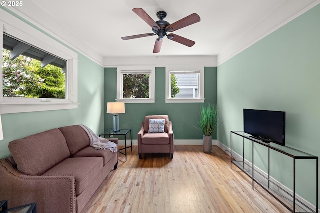 living area with a ceiling fan, hardwood / wood-style floors, and baseboards