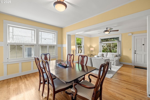dining space with a ceiling fan, light wood-type flooring, baseboards, and crown molding
