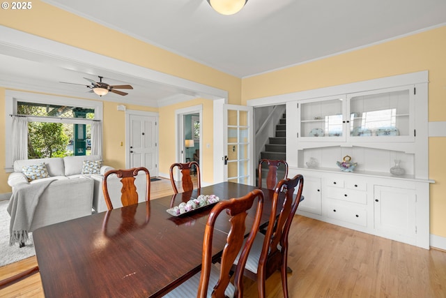 dining area featuring light wood finished floors, ornamental molding, ceiling fan, and french doors