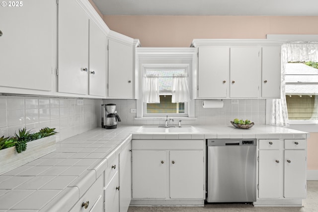kitchen with dishwasher, white cabinetry, tile countertops, a sink, and tasteful backsplash