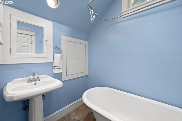 full bathroom featuring a soaking tub, baseboards, and concrete floors