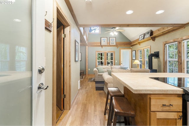 kitchen with a wood stove, recessed lighting, vaulted ceiling, light countertops, and light wood-style floors