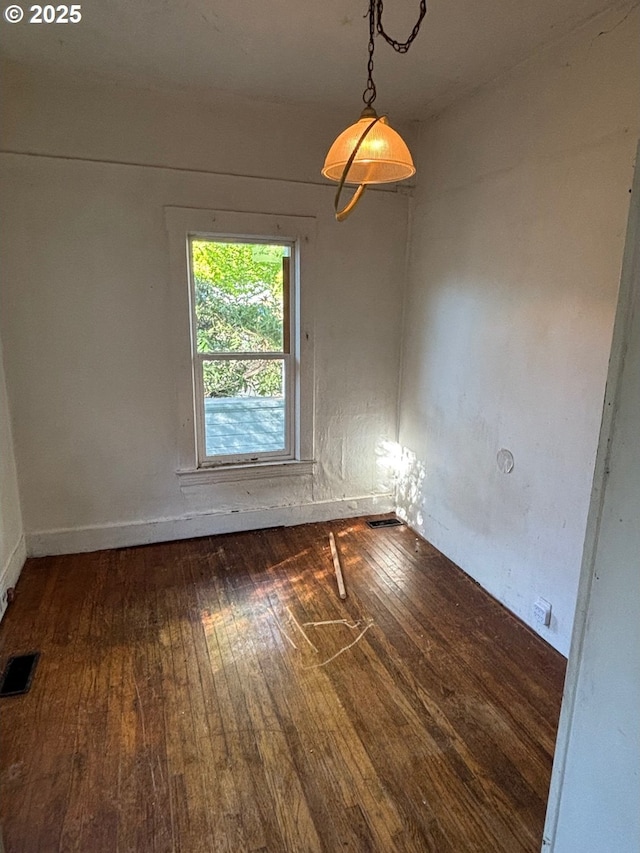 empty room with baseboards, hardwood / wood-style floors, and visible vents
