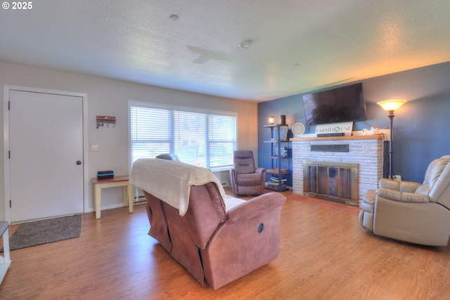 94178 9th St, Gold Beach, OR 97444 - living room with light wood-type flooring, a brick fireplace, and a textured ceiling
