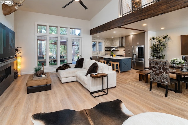 60486 Seventh Mountain Dr, Bend, OR 97702 - living area with a glass covered fireplace, high vaulted ceiling, ceiling fan, and light wood-style flooring