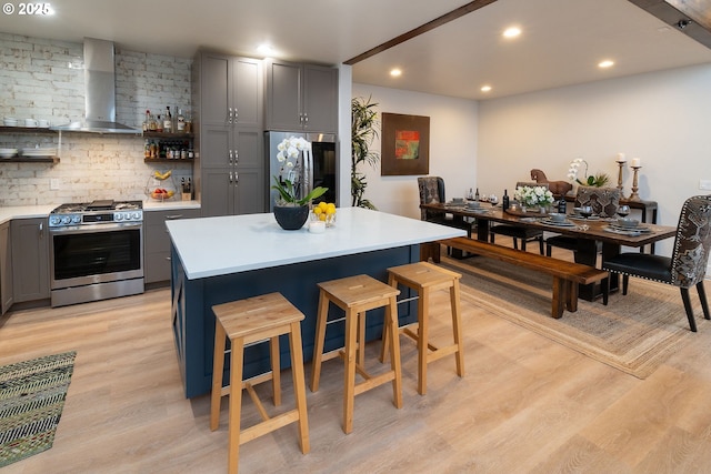 60486 Seventh Mountain Dr, Bend, OR 97702 - kitchen featuring open shelves, light wood-style floors, wall chimney exhaust hood, stainless steel appliances, and gray cabinetry
