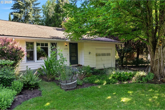 ranch-style house featuring an attached garage, a front yard, and roof with shingles