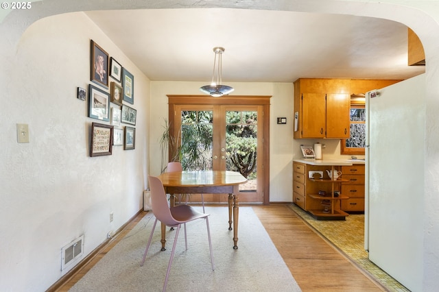 office area featuring visible vents, baseboards, french doors, light wood-style floors, and arched walkways