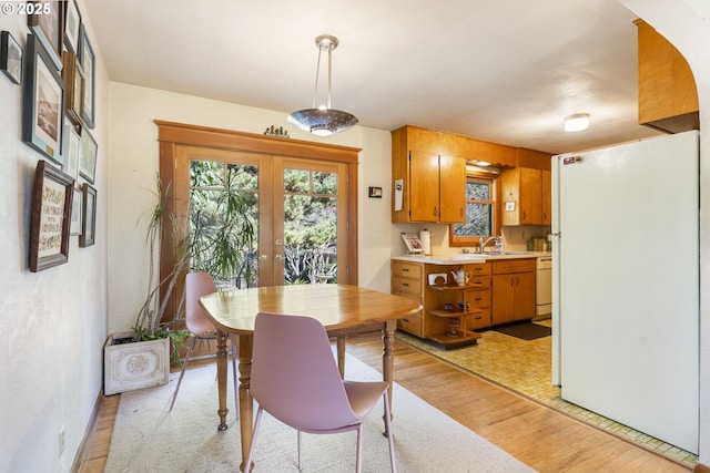 dining space with french doors and light wood-style flooring