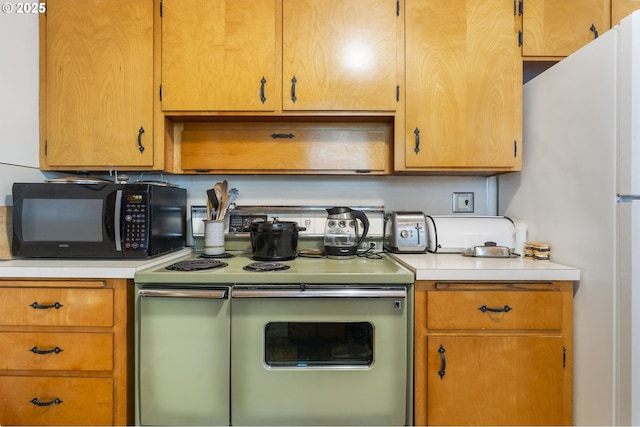 kitchen featuring freestanding refrigerator, light countertops, black microwave, and range with two ovens