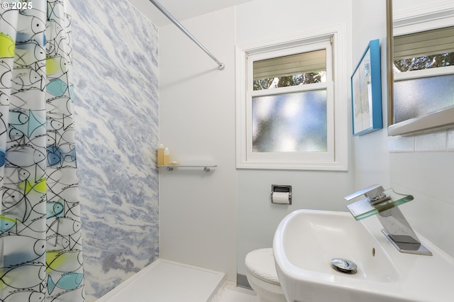 bathroom featuring toilet, a shower with shower curtain, and a sink