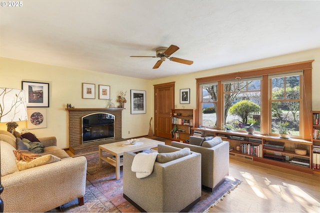 living room with a fireplace, ceiling fan, and wood finished floors