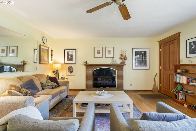 living room with a fireplace, wood finished floors, baseboards, and ceiling fan