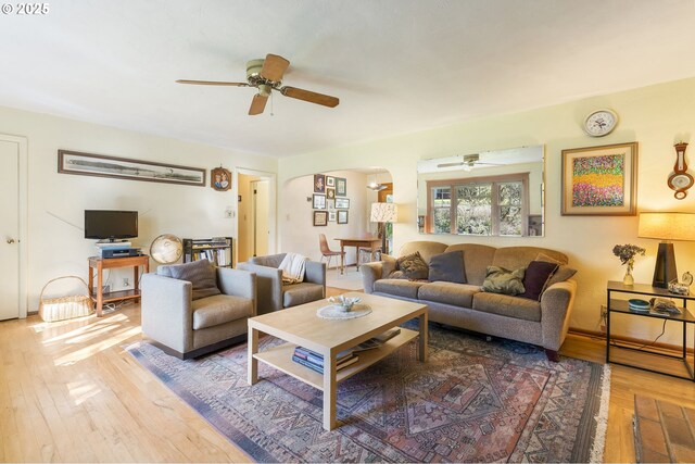 living room with hardwood / wood-style floors, a ceiling fan, and arched walkways