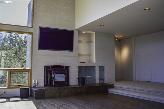 395 Rio Nes Ln, Roseburg, OR 97470 - unfurnished living room featuring wood finished floors, built in shelves, recessed lighting, a wood stove, and a high ceiling