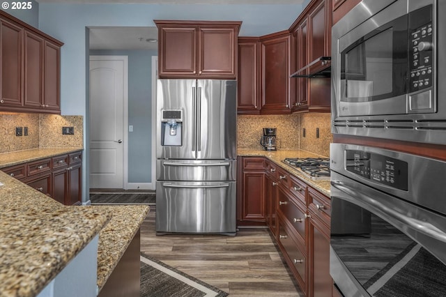 707 N Hayden Island Dr Unit 217, Portland, OR 97217 - kitchen featuring appliances with stainless steel finishes, dark wood-type flooring, light stone counters, and decorative backsplash