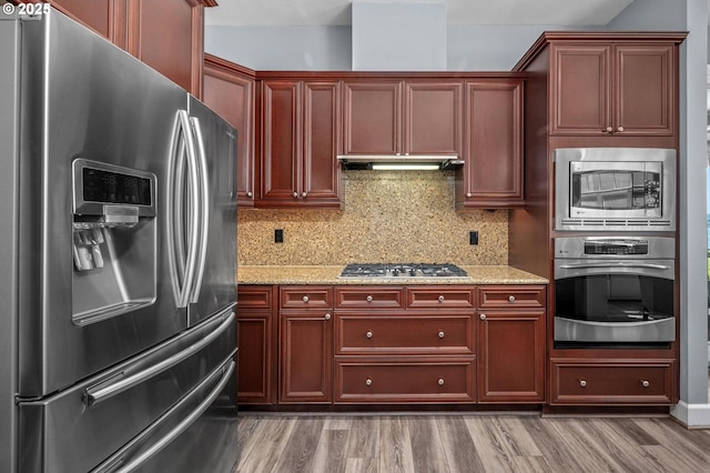 707 N Hayden Island Dr Unit 217, Portland, OR 97217 - kitchen with appliances with stainless steel finishes, reddish brown cabinets, tasteful backsplash, and light stone countertops