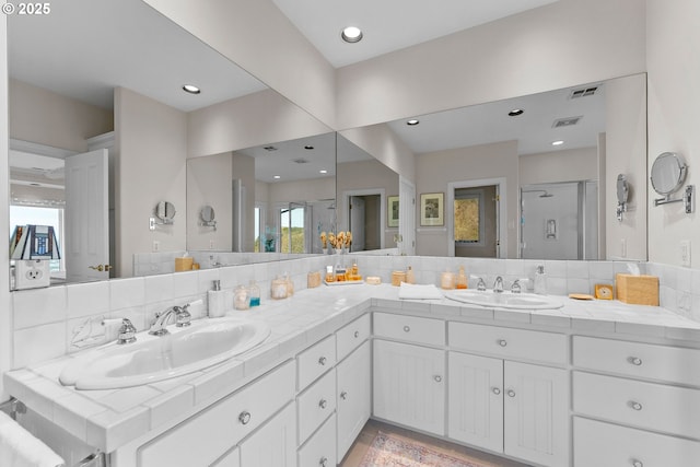 full bath featuring a stall shower, visible vents, decorative backsplash, and a sink