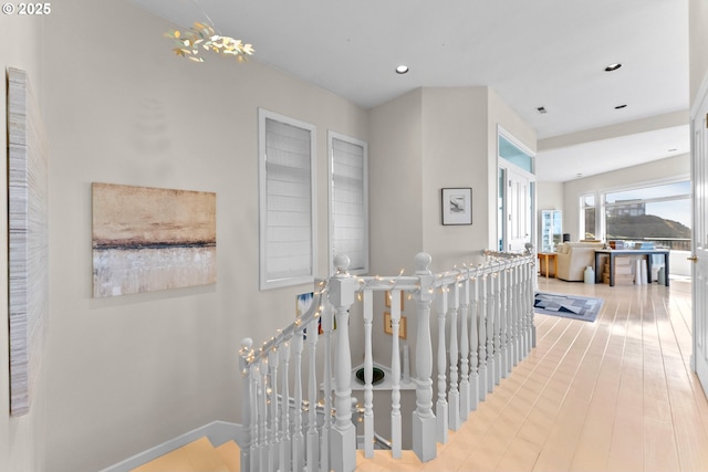 hallway with baseboards, wood finished floors, an upstairs landing, and recessed lighting