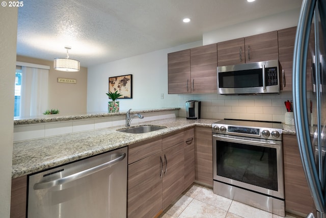 kitchen with a sink, brown cabinetry, stainless steel appliances, backsplash, and pendant lighting