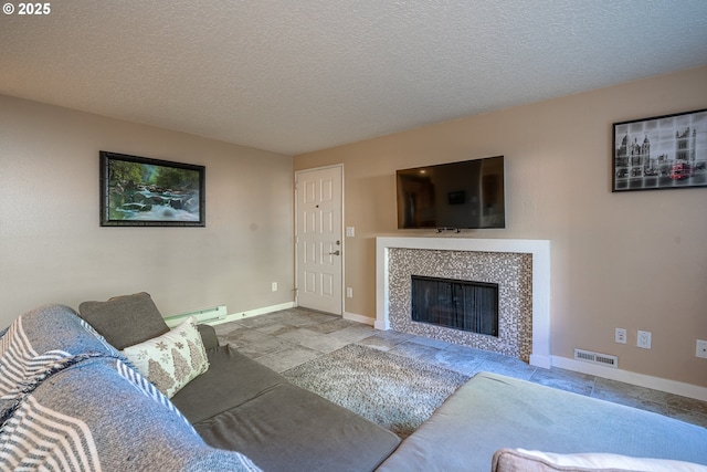 living area with baseboard heating, a textured ceiling, a tiled fireplace, baseboards, and visible vents