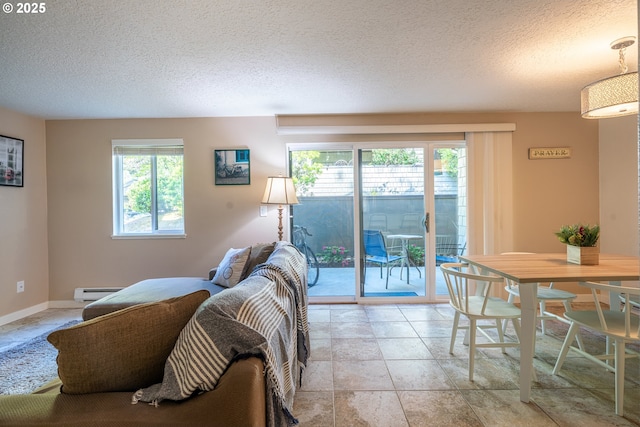 living area with a textured ceiling, a healthy amount of sunlight, stone finish floor, and baseboard heating