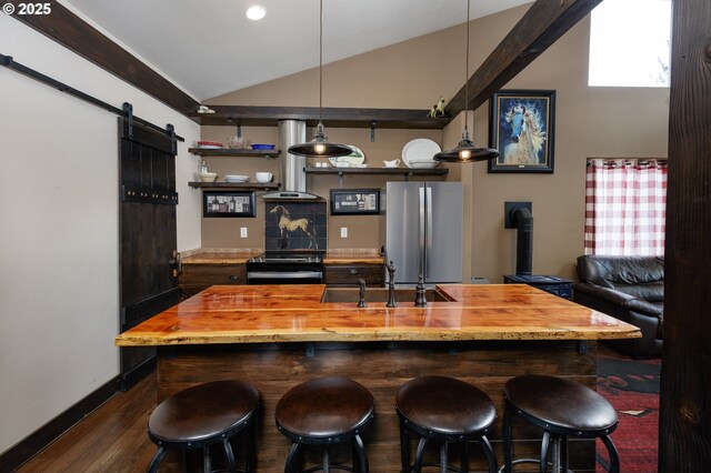bar featuring freestanding refrigerator, a sink, lofted ceiling, wall chimney range hood, and a barn door