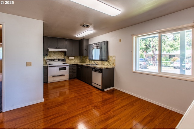 47508 Hansen St, Oakridge, OR 97463 - kitchen with white appliances, dark wood-style flooring, under cabinet range hood, tasteful backsplash, and baseboards