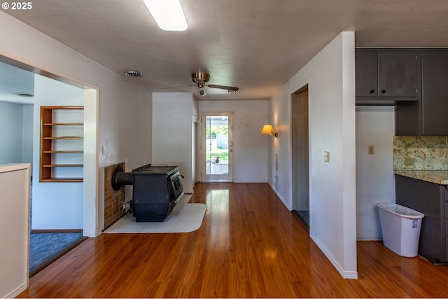 47508 Hansen St, Oakridge, OR 97463 - unfurnished living room featuring a wood stove, wood finished floors, baseboards, and ceiling fan