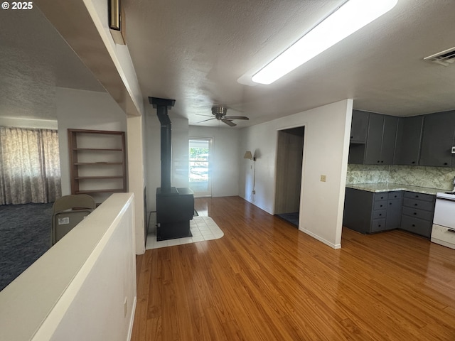 47508 Hansen St, Oakridge, OR 97463 - unfurnished living room featuring a wood stove, a textured ceiling, ceiling fan, and light wood-type flooring
