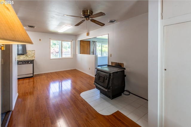 47508 Hansen St, Oakridge, OR 97463 - unfurnished living room with a wood stove, a ceiling fan, wood finished floors, and baseboards