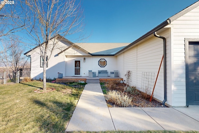 view of front of house with fence, a deck, and a front lawn