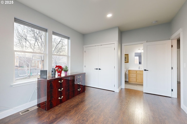 bedroom featuring ensuite bath, dark wood-type flooring, and a closet