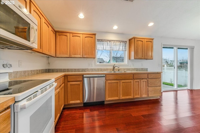 kitchen featuring white appliances, dark hardwood / wood-style flooring, and sink