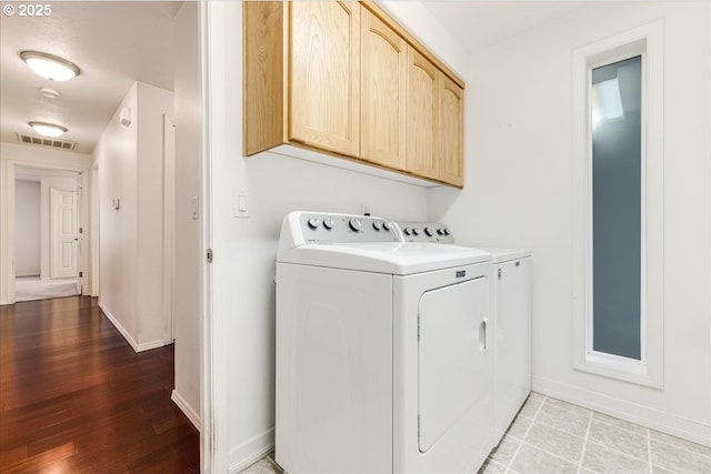 laundry room with hardwood / wood-style floors, washer and clothes dryer, and cabinets