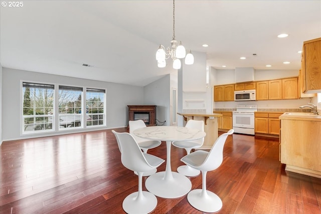 dining room with lofted ceiling, sink, dark hardwood / wood-style flooring, and an inviting chandelier