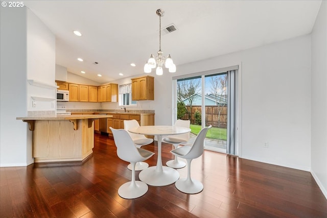 dining space with sink, dark hardwood / wood-style floors, a chandelier, and vaulted ceiling