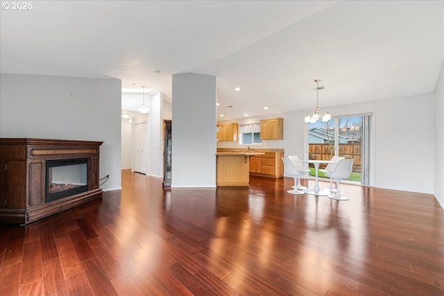 unfurnished living room featuring a notable chandelier, sink, and dark hardwood / wood-style floors