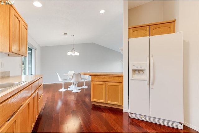 kitchen featuring pendant lighting, dark hardwood / wood-style flooring, white fridge with ice dispenser, light brown cabinetry, and vaulted ceiling