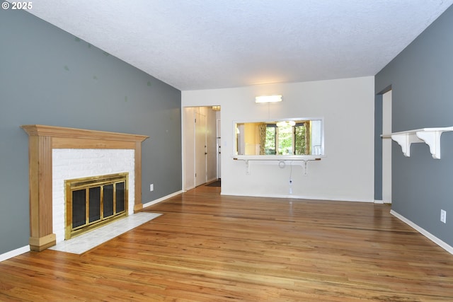 4296 SE Fieldcrest St, Milwaukie, OR 97222 - unfurnished living room with wood finished floors, a brick fireplace, and a textured ceiling